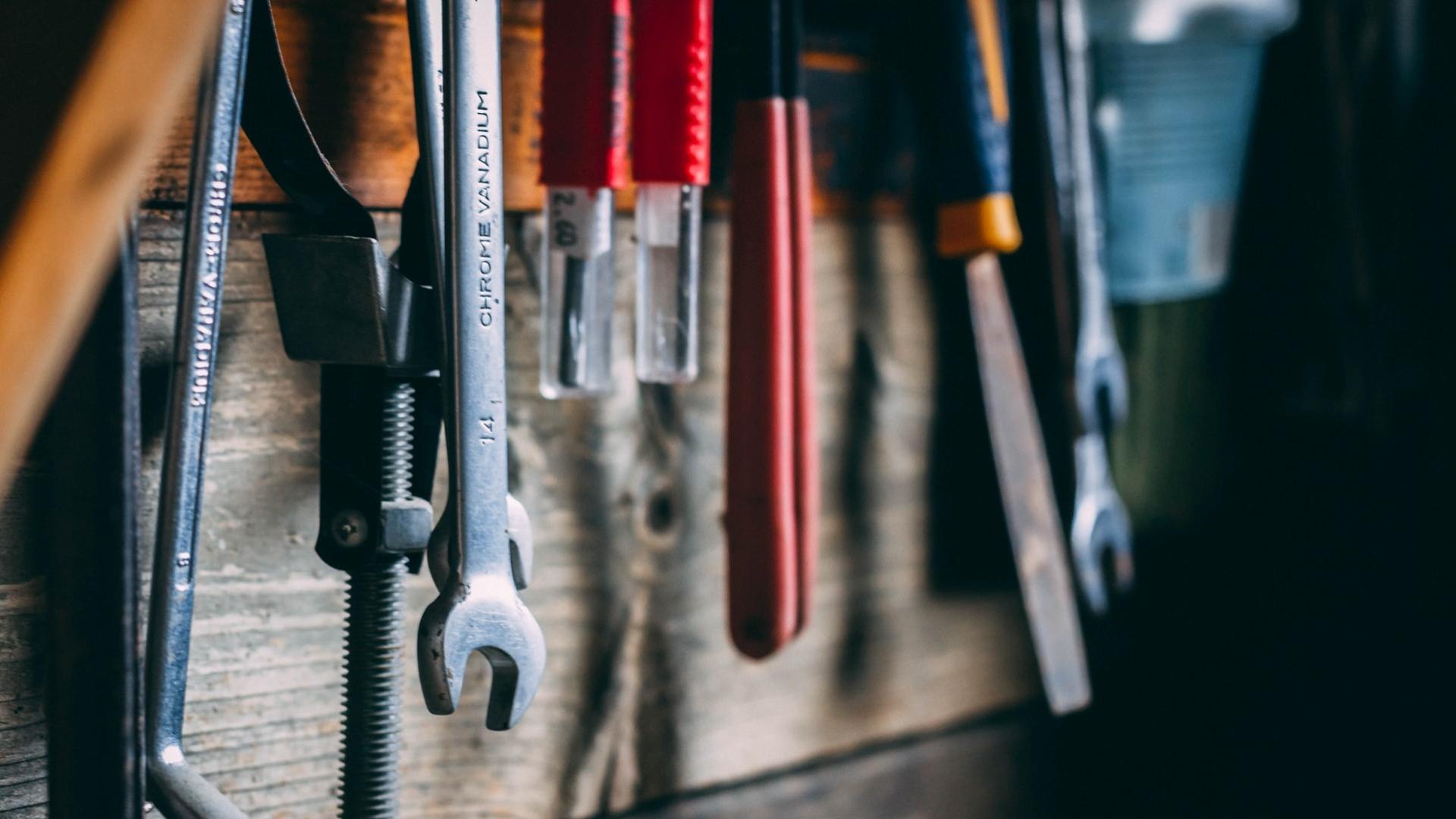 An assortment of tools hanging on a wooden wall