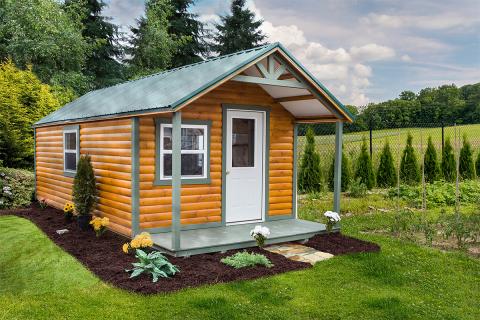 Signature hunter cabin with brown half log siding, a front porch, windows, a white front door with a window, and a metal roof.